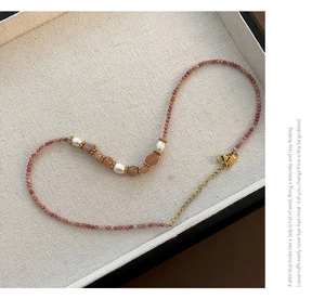 Détail d'un collier de perles avec pierres roses facettées et fermoir doré
