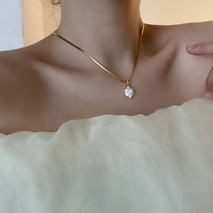 Elegant gold snake chain necklace with white turtle pendant on woman neck