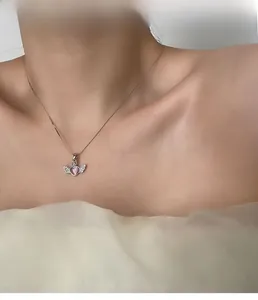 Close-up of pink heart with wings pendant on a silver necklace worn by a model