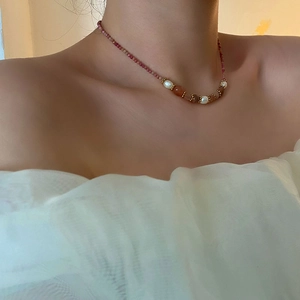 Collier élégant en perles naturelles avec pierres brun-rouge sur le cou d'un modèle