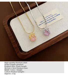 Collier pendentif pomme en zircon rose sur lin dans un plateau en bois rustique