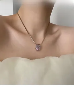 Gros plan d'un mannequin portant un collier avec pendentif en zircon rose et chaîne serpent