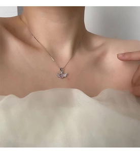 Close-up of pink heart wing pendant necklace with crystals on a female model