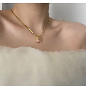Gros plan d'une chaîne serpent dorée avec pendentif en pierre rose sur mannequin