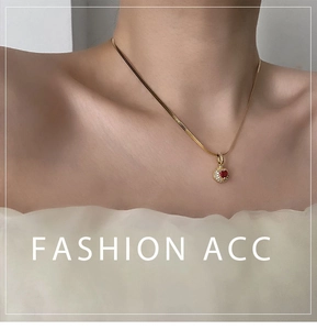 Close-up of gold chain necklace with a red heart-shaped gemstone pendant on a female model