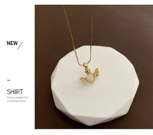 Detail of angel wing heart pendant with white gemstone and pavé stones on a gold chain