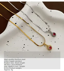 Detail of gold and silver snake chains with red heart zircon pendants on a ceramic tray