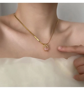 Détail du pendentif ours rose sur une chaîne serpent dorée portée au cou