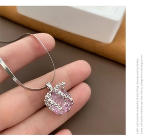 Gros plan du pendentif en zircon rose avec texture artistique et chaîne serpent fine