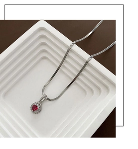 Macro detail of red heart-shaped zircon pendant with sparkling white stone halo