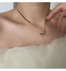 Close-up of a gold snake chain necklace featuring a sparkling red heart zircon pendant
