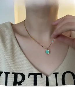 Dettaglio della modella che indossa una collana d'oro con perline colorate e ciondolo smiley