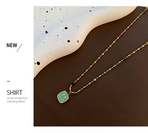 Dettaglio della collana a sfere dorate con perle colorate e ciondolo sorriso menta