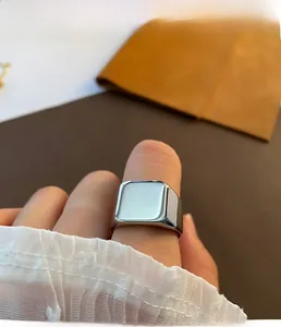 Close-up of a square silver signet ring in polished stainless steel worn on the finger