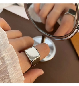 Close-up of minimalist silver rectangular signet ring reflected in a round mirror
