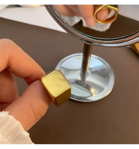 Close-up of a minimalist gold-plated stainless steel signet ring with a square flat face