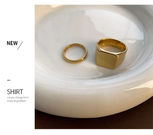 Close-up of golden titanium steel signet ring and minimalist band in a ceramic dish