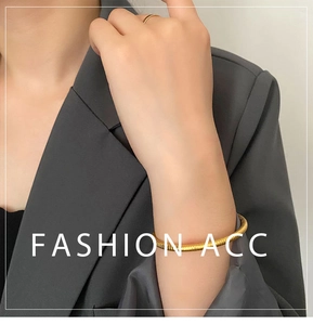 Close-up of golden snake pattern cuff bracelet and minimalist slim ring on female wrist