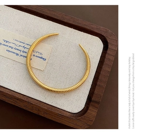 Detailed macro shot of a gold-toned cuff bracelet with textured horizontal grooves