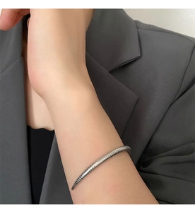 Close-up of minimalist silver open cuff bracelet with industrial ribbed texture on wrist