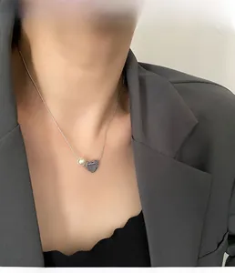 Close-up of geometric heart necklace with pearl detail on a female model