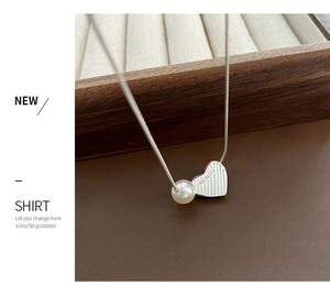 Detail of silver snake chain necklace with pearl and BEAUTY engraved heart pendant