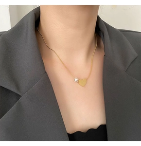 Close-up of a gold heart pendant with a pearl on a titanium steel necklace chain