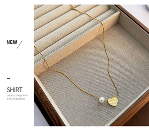 Detail of gold titanium heart necklace with pearl pendant and BEAUTY engraving