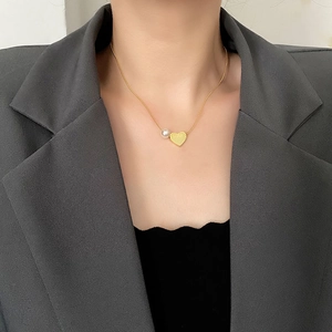 Minimalist gold heart necklace with a round white pearl on a snake chain pendant