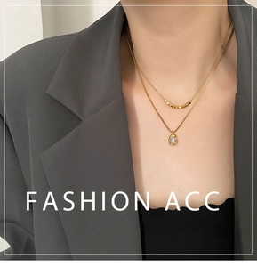Gros plan d'un collier double épaisseur doré avec petites perles et pendentif nacré