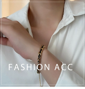 Detailed view of woven black leather and gold titanium steel chain bracelet with lobster clasp