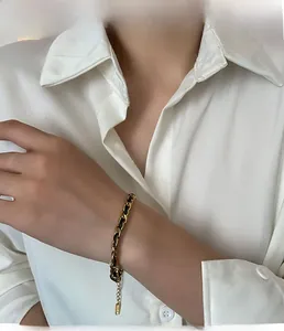 Detail of gold titanium steel and black leather woven bracelet with adjustable chain