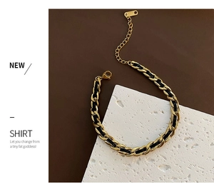 Detail of gold titanium chain bracelet with black woven cord and lobster clasp closure