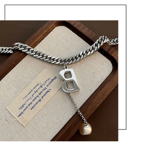 Detailaufnahme der silbernen Gliederkette mit B-Anhänger und Perle auf Holztablett