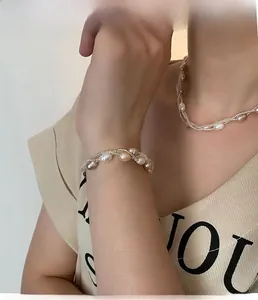 Détail d'un ensemble collier et bracelet en perles baroques avec fines chaînes dorées