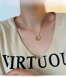 Minimalist golden twisted ring pendant necklace shown on a model wearing a V-neck shirt