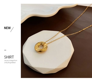 Detail of twisted gold ring pendant with hammered texture on a dainty O-chain link necklace