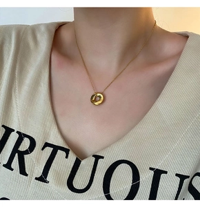 Close-up of a gold twisted pendant necklace on a model with a delicate O-link chain
