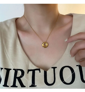 Close-up of golden twisted pendant necklace on female model for elegant jewelry styling