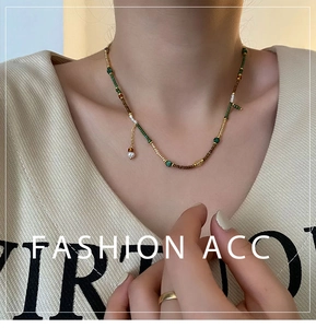Detail of beaded ethnic necklace with green stones and pearl pendant on neck