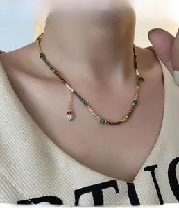 Detail of beaded necklace with emerald, coffee beads and white pearl accents on model