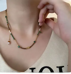 Detail view of ethnic style beaded necklace with green beads and pearl pendant