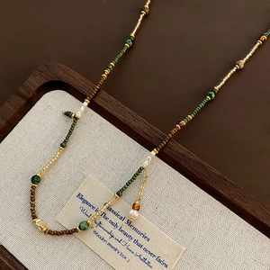 Retro multi-material beaded pearl necklace on vintage wooden display tray with linen liner
