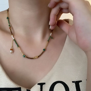 Vintage beaded necklace with green and gold accents and small white pearl pendant