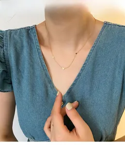Gros plan d'un collier doré avec pendentifs cœurs porté par un mannequin en jean