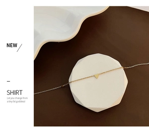Détail d'un collier pendentif cœur en or minimaliste exposé sur un support en marbre