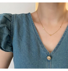 Gros plan d'un collier en chaîne dorée avec trois petits pendentifs en forme de cœur