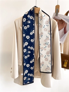 Détail d'une écharpe fleurie double face drapée sur un blazer beige classique élégant