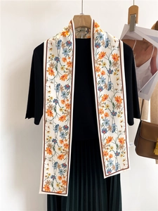 Détail d'un foulard étroit à imprimé floral double face sur une robe noire fluide