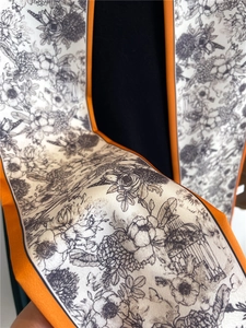 Détail d'un foulard en soie vintage avec motifs floraux, cage à oiseaux et bordure orange